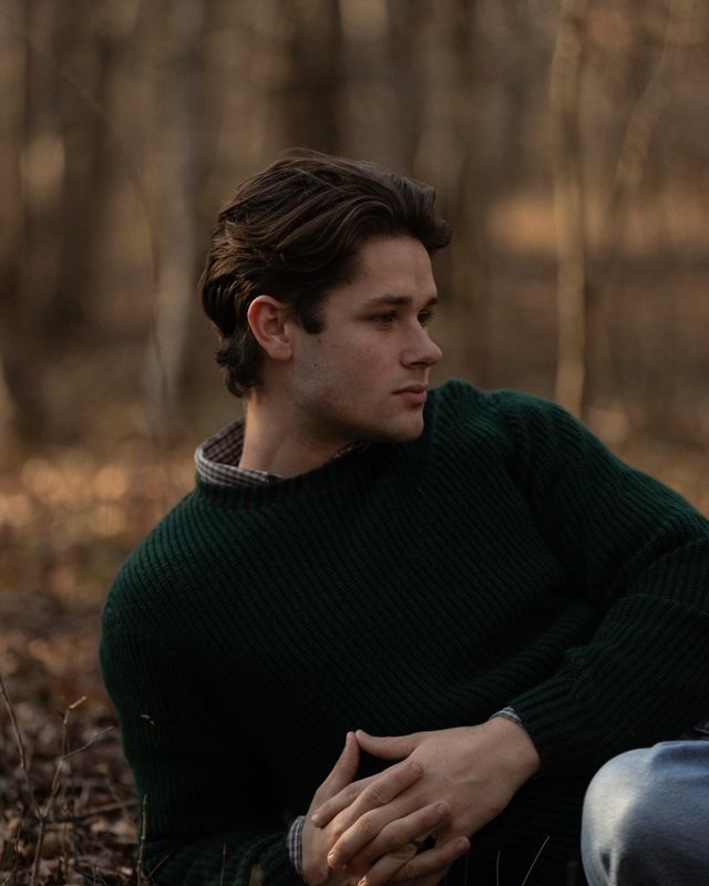 Portrait of Daniel Mercer in a green sweater, seated outdoors