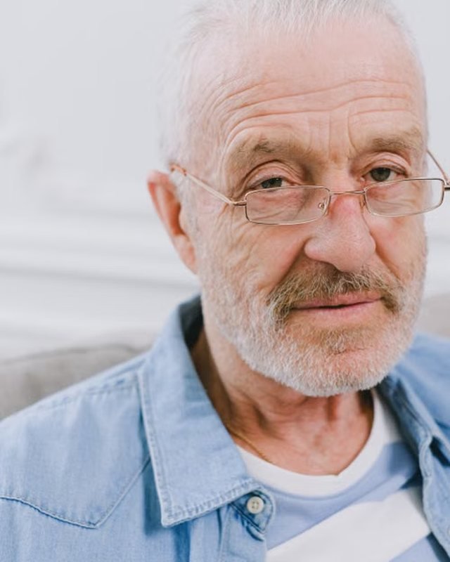 Portrait of Elliot Crane wearing glasses and a denim shirt